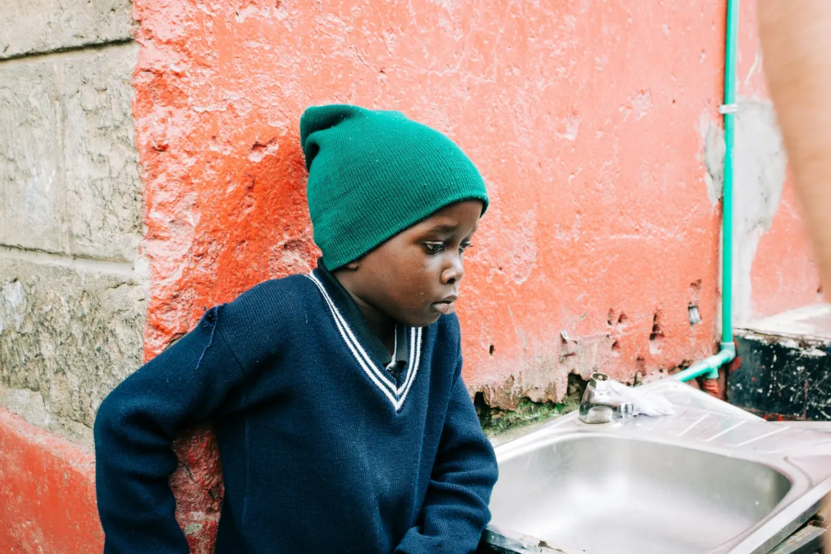 A young boy in a green beanie beside an orange wall