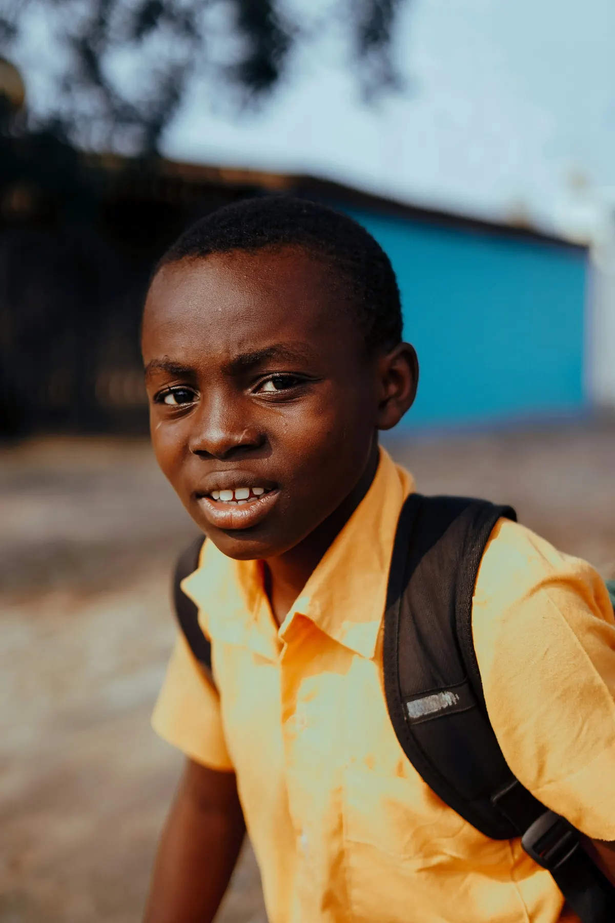 A schoolboy with a backpack smiling at the camera