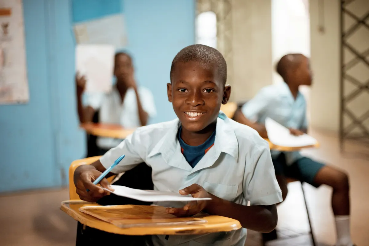 A smiling schoolboy at his desk in a classroom