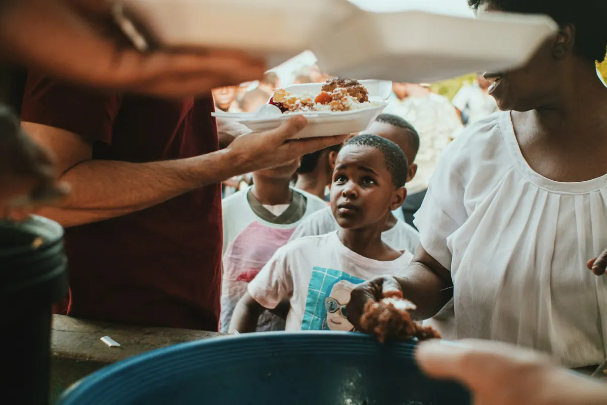 Volunteers hand plates of food to children