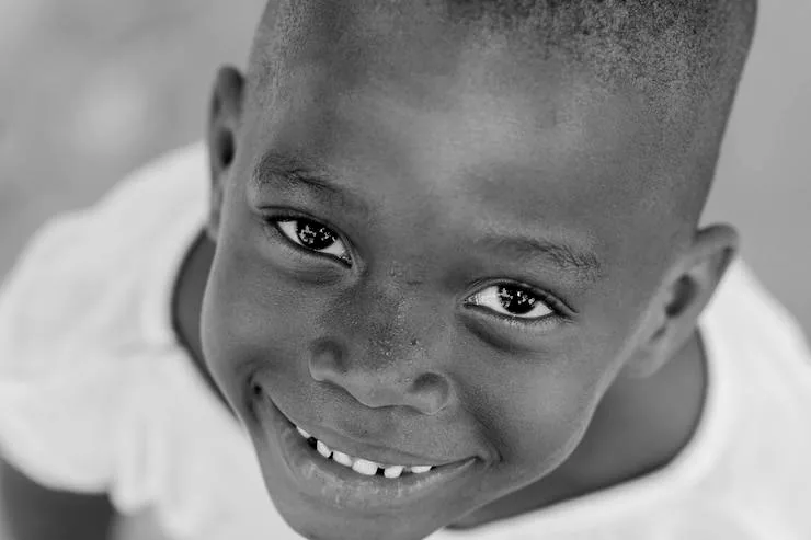 A young boy smiling at the camera, in black and white